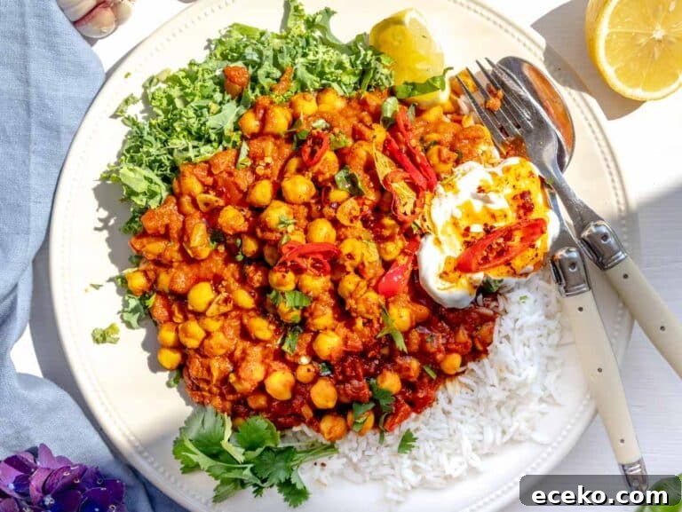 Chana masala served on a plate with kale, yogurt, and chili oil