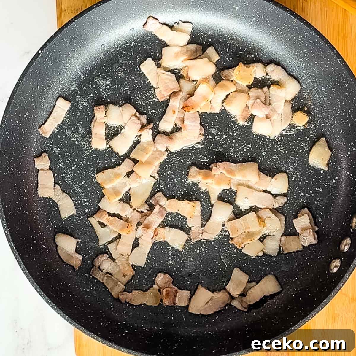 chopped bacon cooking in a pan.