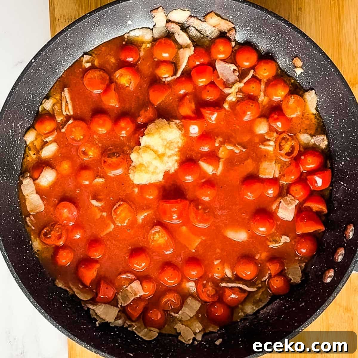 horseradish, tomato juice, and worcestershire sauce are added to cooking cherry tomatoes, bacon, and garlic in pan.