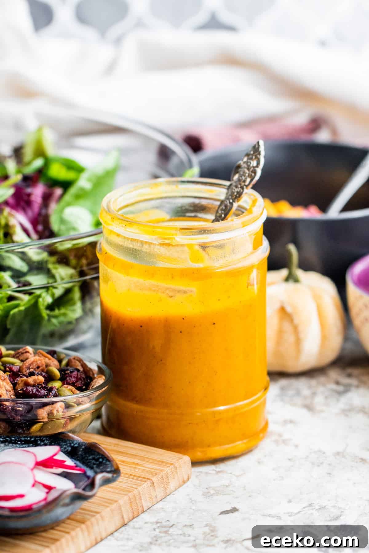 Dressing in a glass jar with salad stuff around it.