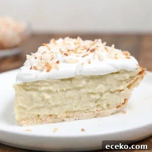 A slice of Coconut Cream Pie with a flaky crust, creamy coconut filling, topped with whipped cream and toasted coconut flakes, served on a white plate for the perfect tropical dessert.
