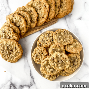 Baked chocolate chip cookies sitting in a bowl and surrounded by a swirl of cookies.