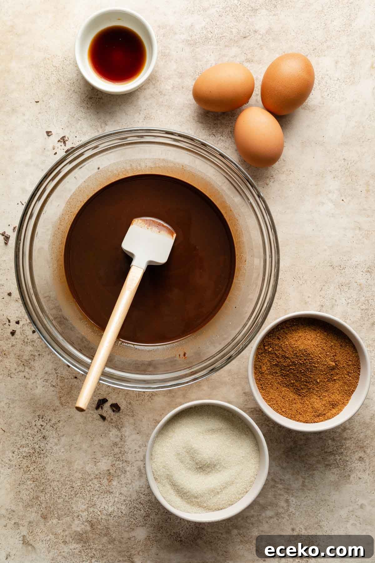 Melted chocolate in a bowl next to sugar and eggs.