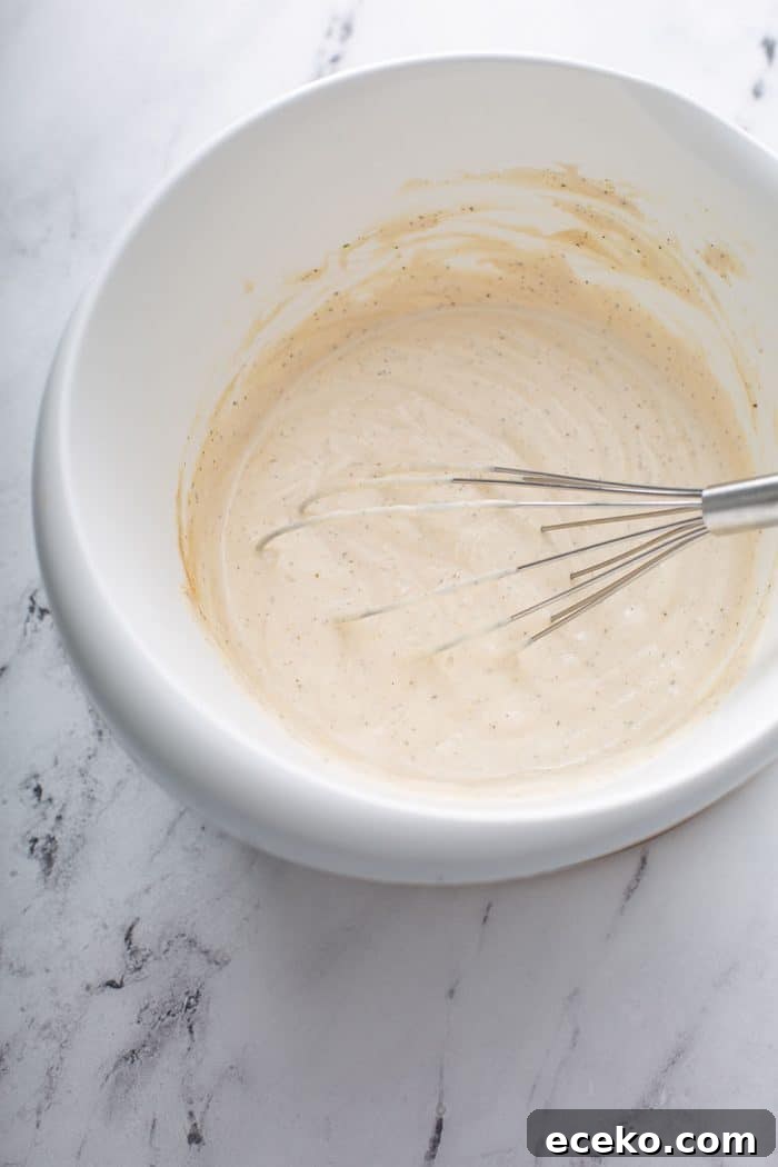 Creamy Homemade French Onion Dip Recipe for Parties 6 Whisk combining sour cream, mayo, and seasonings in a white mixing bowl