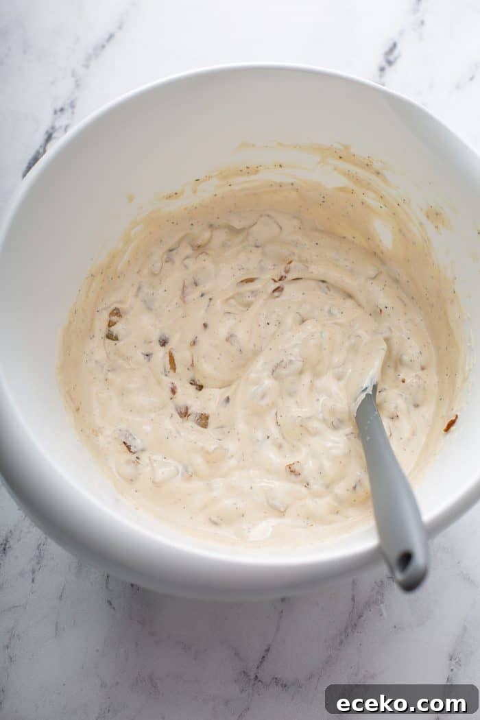Creamy Homemade French Onion Dip Recipe for Parties 7 Spoon stirring french onion dip in a white bowl