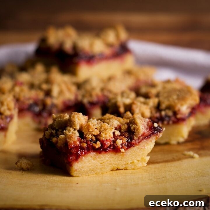 A wood serving platter stacked with cherry shortbread crumble bars.