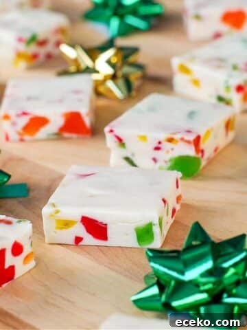 Nougat candy, cut into squares, on a wooden cutting board with green and gold mini bows
