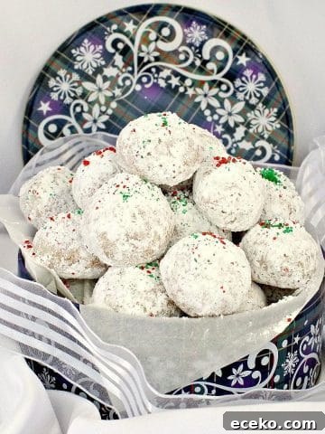 Almond Snowball cookies in a blue Christmas cookie tin, with ribbon around it