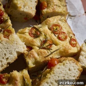 Slices of focaccia topped with cherry tomatoes on white parchment paper.