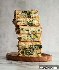 Spinach Artichoke Grilled Cheese 6 sandwich halves stacked on each other with filling dripping out