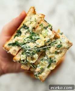 Spinach Artichoke Grilled Cheese overhead shot of hand opening 3 sandwich halves to show filling