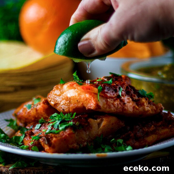 Someone squeezing lime juice over a plate of adobo fish.