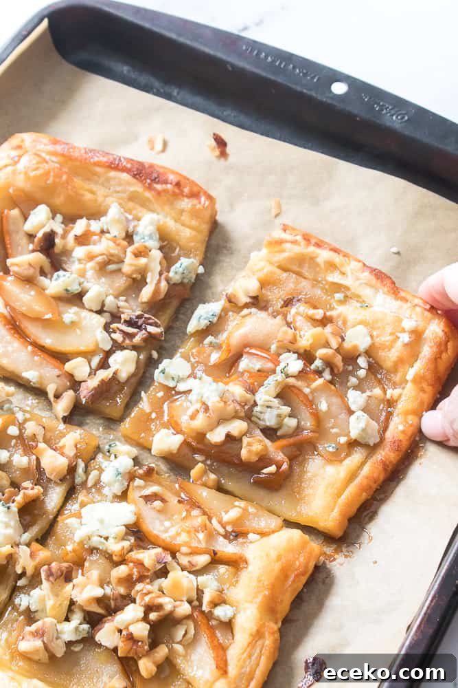 Caramelized Pear & Blue Cheese Tartlets for Entertaining 2 hand reaching for pear and blue cheese tart on baking sheet