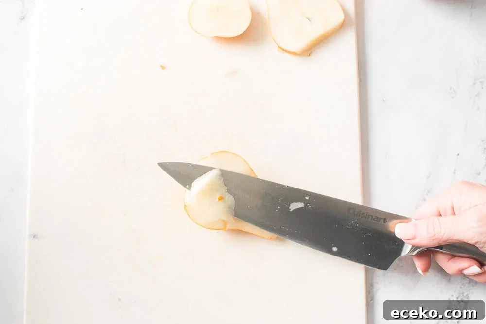 Caramelized Pear & Blue Cheese Tartlets for Entertaining 5 pear on cutting board cut in half with knife removing pit