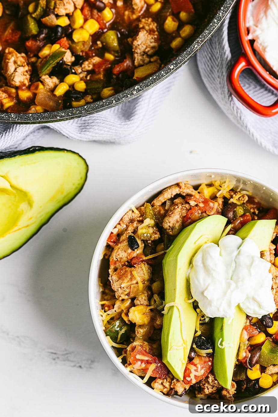 One-Skillet Taco Skallowder: Quick Mexican-Style Skillet Dinner 6 overhead image: a bowl of taco skillet topped with two slices of avocado, some shredded cheddar cheese and a dollop of greek yogurt