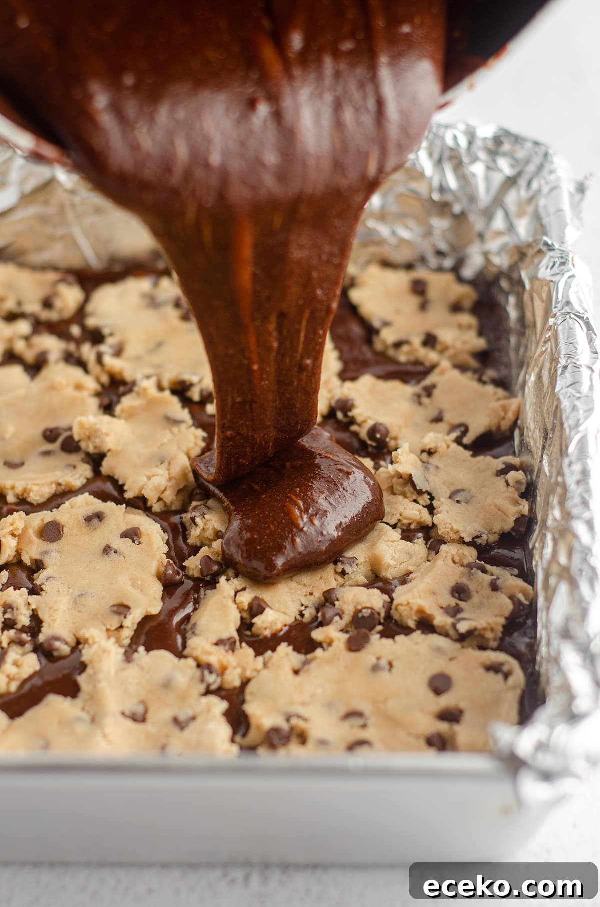 Cookie Dough Stuffed Brownies: Decadent Chocolate Dessert Recipe 13 pouring brownie batter onto cookie dough layer