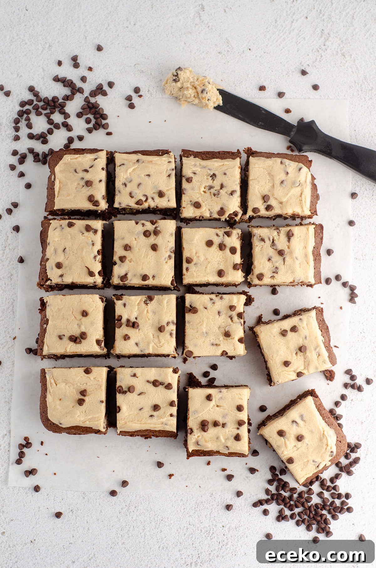 Cookie Dough Stuffed Brownies: Decadent Chocolate Dessert Recipe 4 aerial photo of cookie dough brownies with cookie dough buttercream, scattered with mini chocolate chips and a spatula with buttercream on it