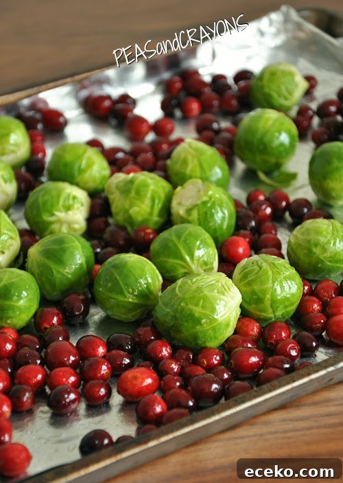 brussels sprouts and fresh cranberries on a foil lined baking sheet