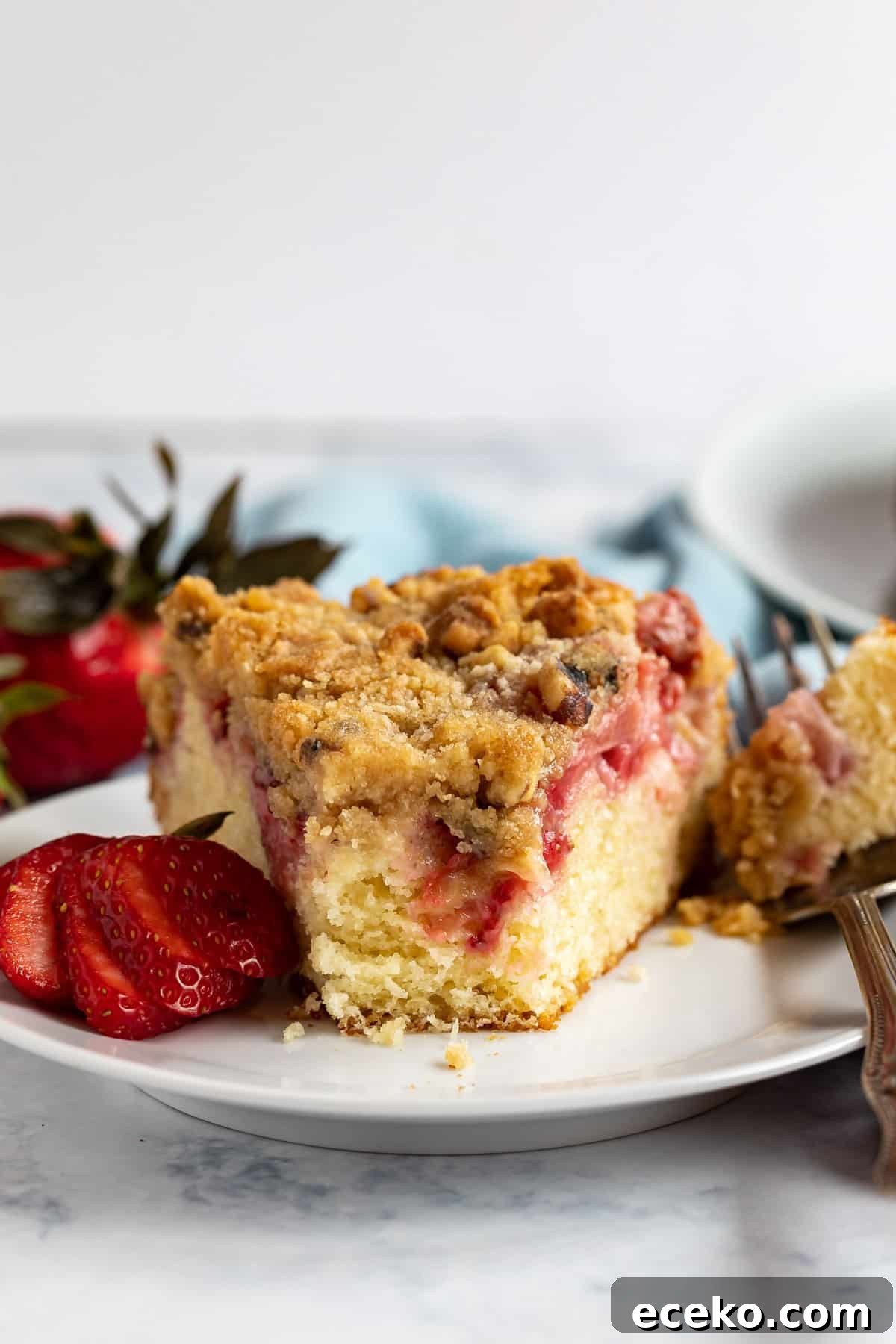 Strawberry Shortcake Crumb Cake Recipe — Moist Summer Dessert 2 Strawberry Cake on a plate with a bite taken out revealing the inside of the cake.