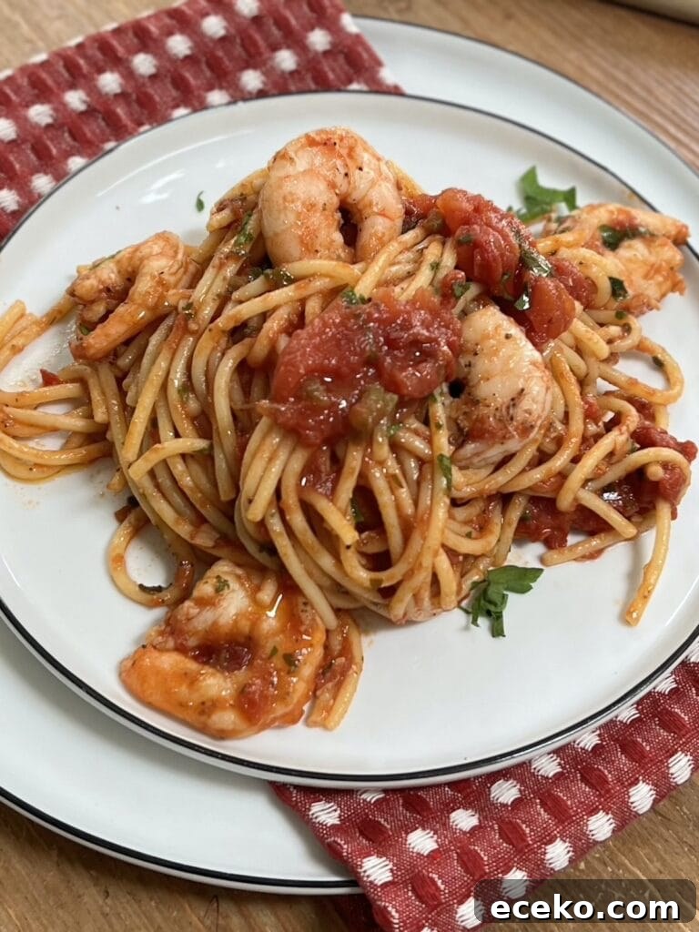 Spicy Shrimp Arrabbiata Pasta with Garlic Tomato Sauce 2 Spicy shrimp arrabbiata pasta on white dinner plate over red decorative towel.
