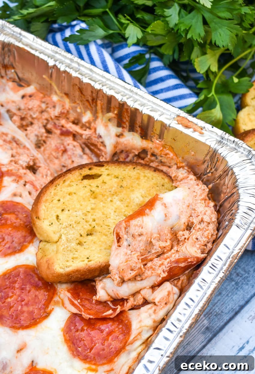 garlic texas toast scooping smoked pepperoni pizza dip out of an aluminum baking dish