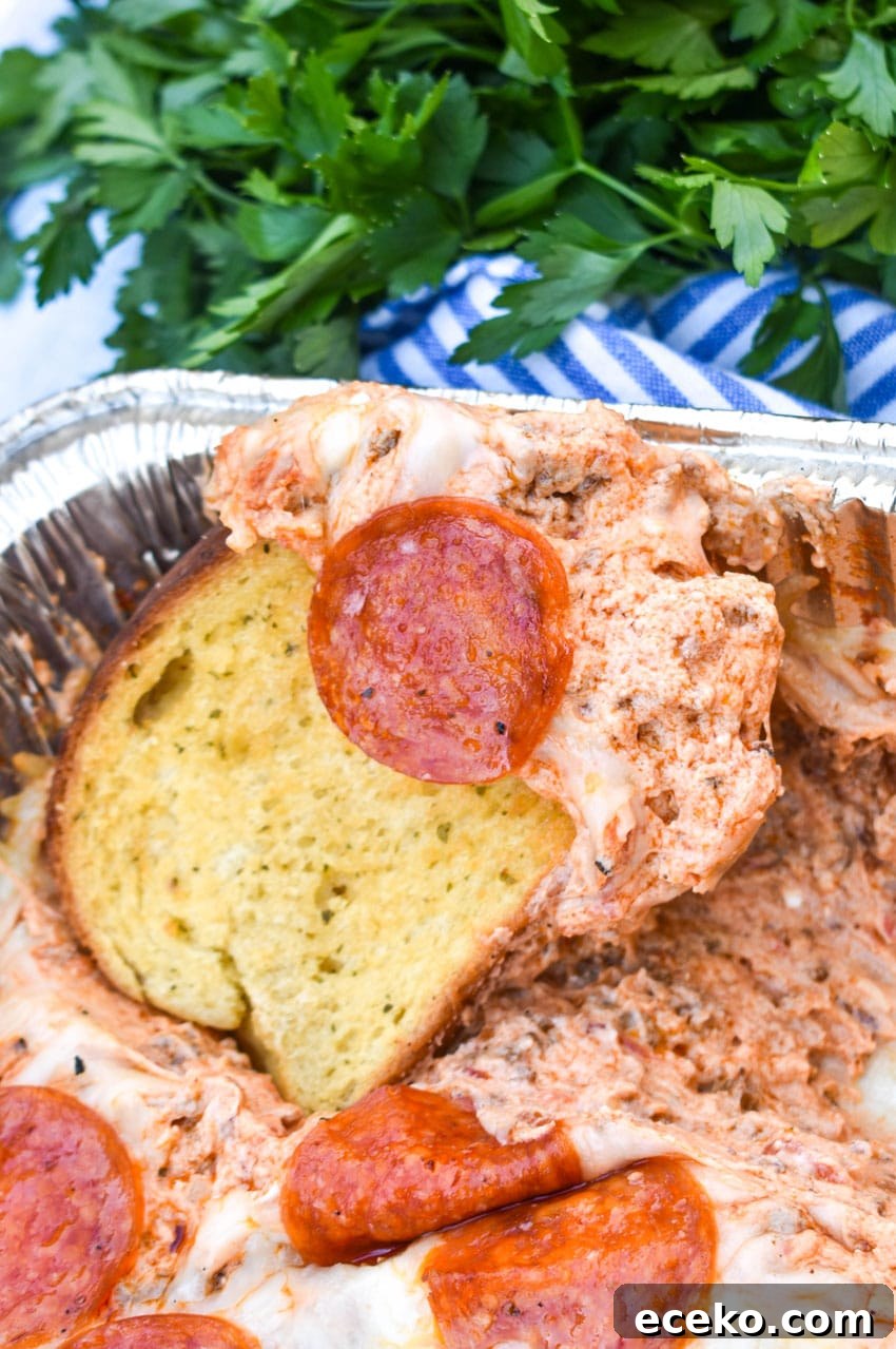 garlic texas toast scooping smoked pepperoni pizza dip out of an aluminum baking dish