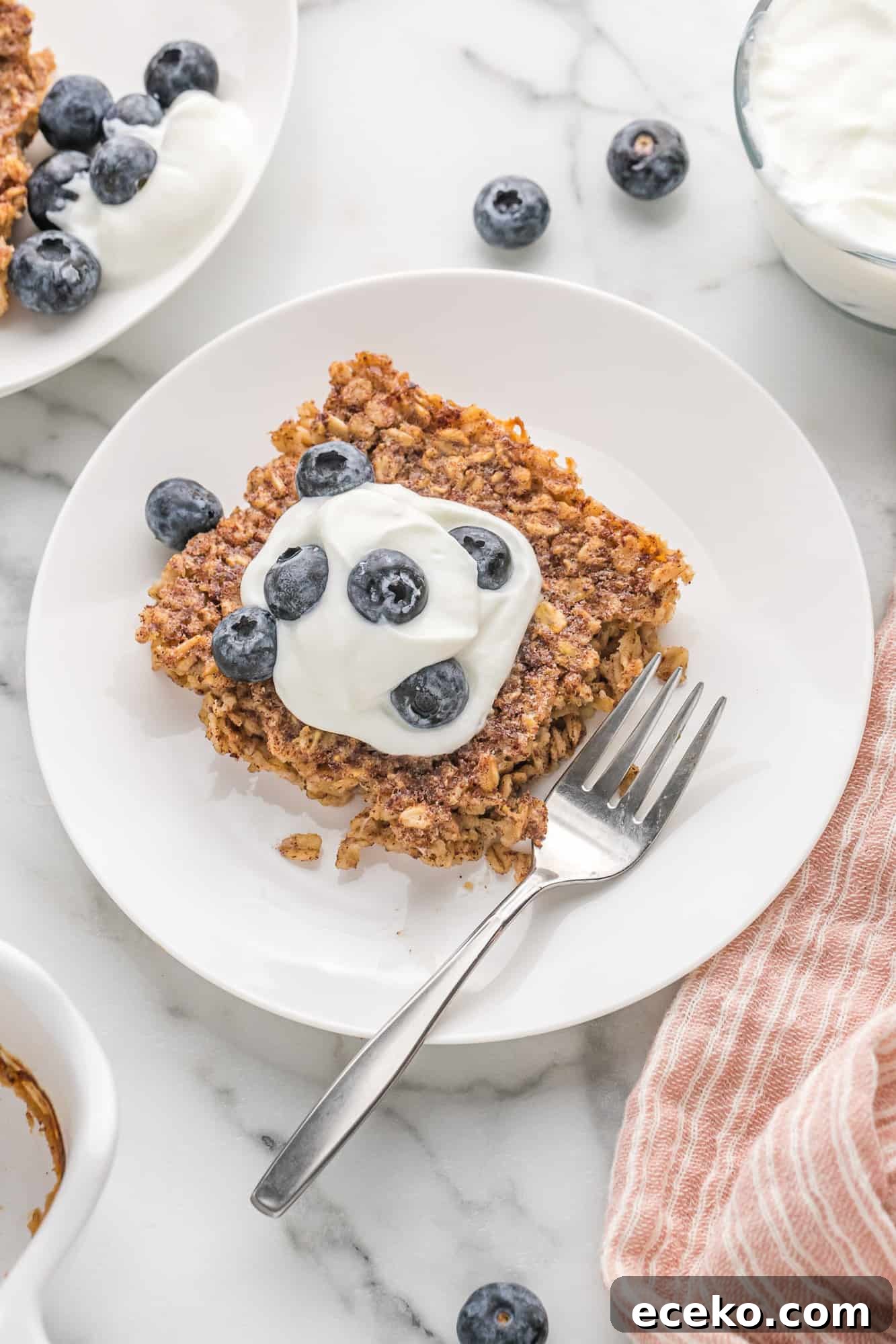 Baked Oatmeal Recipe with Flavor Ideas and Variations 2 Square of baked oatmeal topped with yogurt and blueberries.