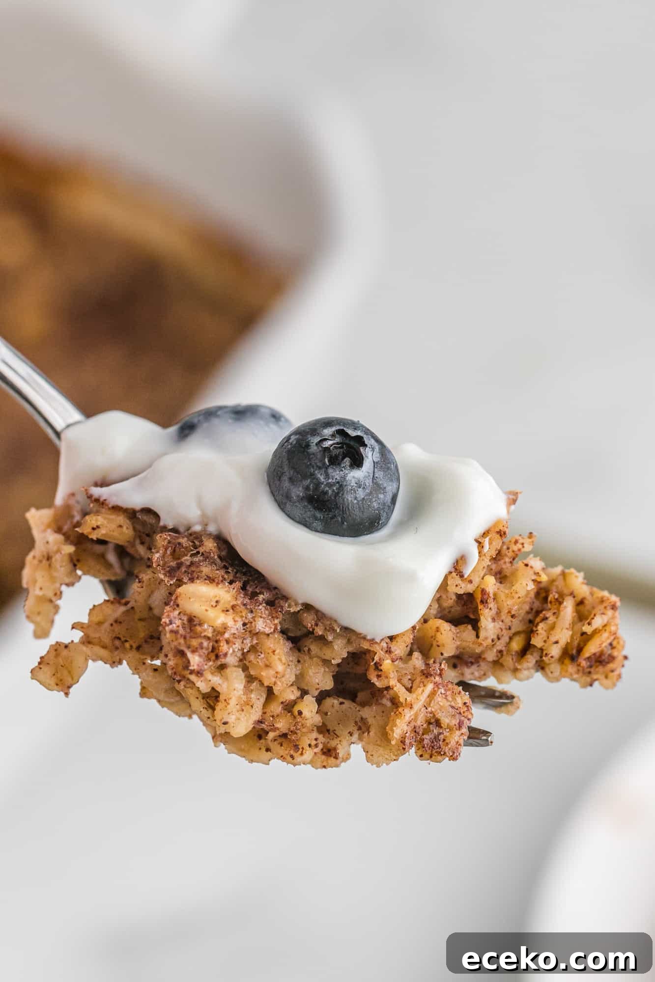 Baked Oatmeal Recipe with Flavor Ideas and Variations 8 Baked oatmeal on a fork with yogurt and blueberries.