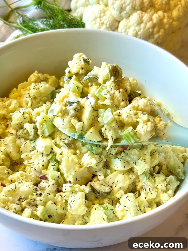 Roasted Cauliflower and Potato Salad with Herb Vinaigrette 7 Finished cauliflower potato salad in a bowl with a serving spoon.