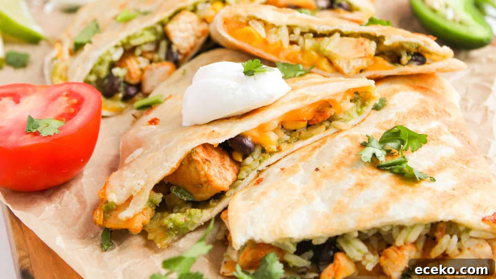 Quesadillas filled with rice, beans, and chicken, topped with sour cream and cilantro. Sliced tomato and jalapeño are on the side.