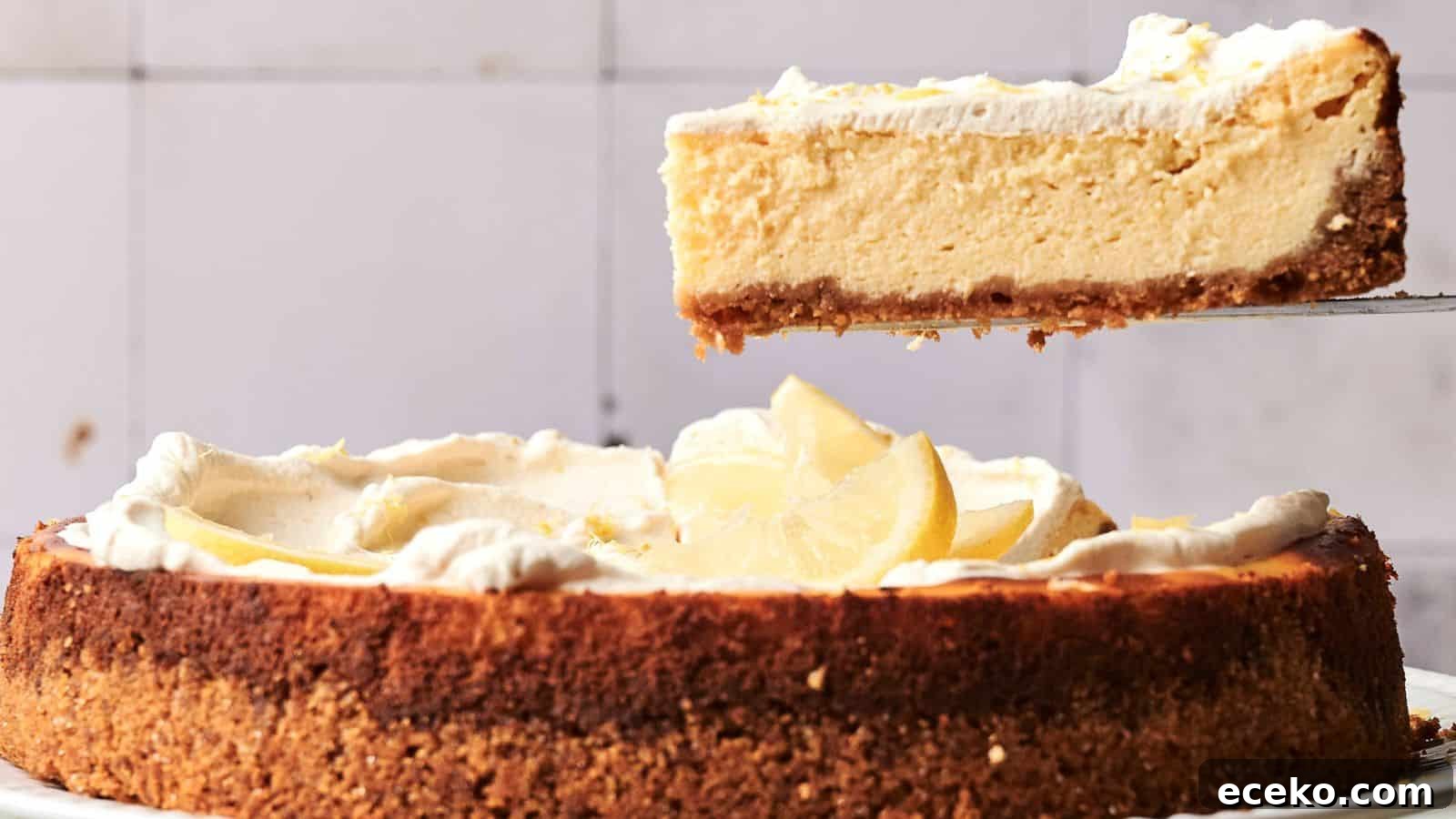 A slice of lemon cheesecake with a graham cracker crust is being lifted from the whole cake, which is topped with whipped cream and lemon slices.