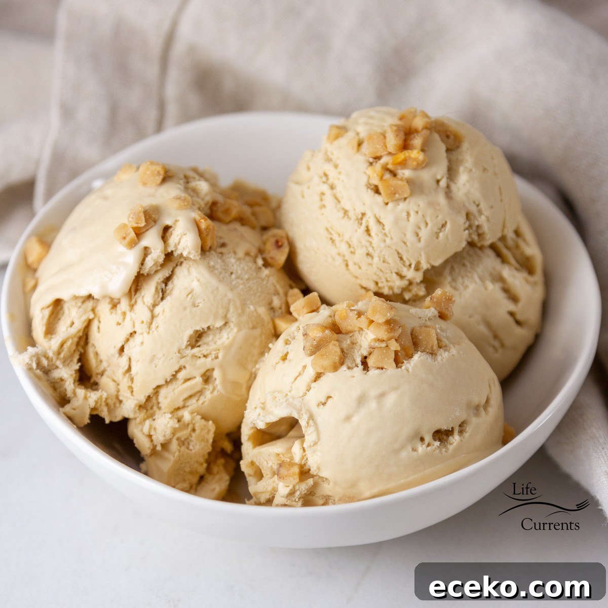 square crop of a bowl of ice cream topped with toffee pieces.