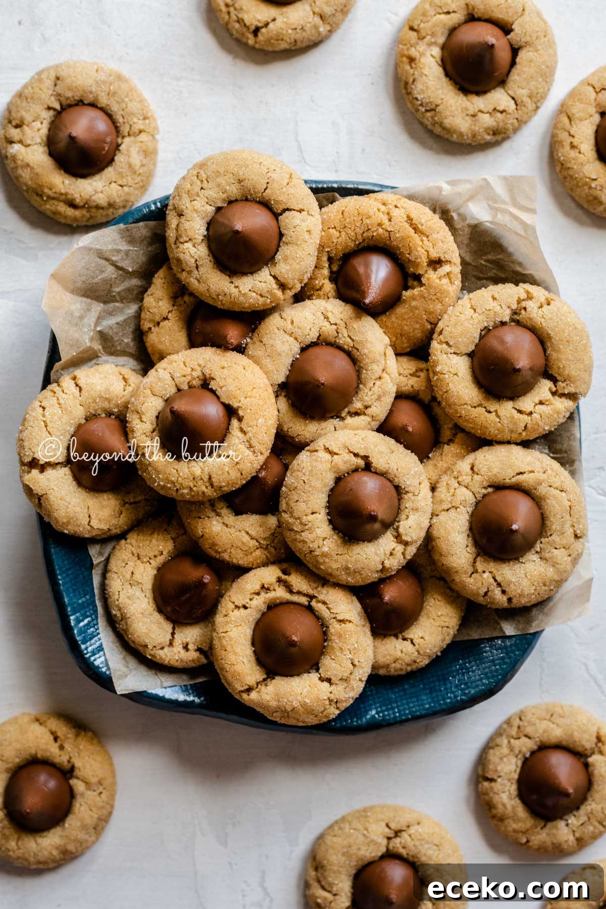 Classic Peanut Butter Blossoms Cookie Recipe 2 Overhead image of classic peanut butter blossoms on a parchment lined blue dessert platter | All Images © Beyond the Butter™