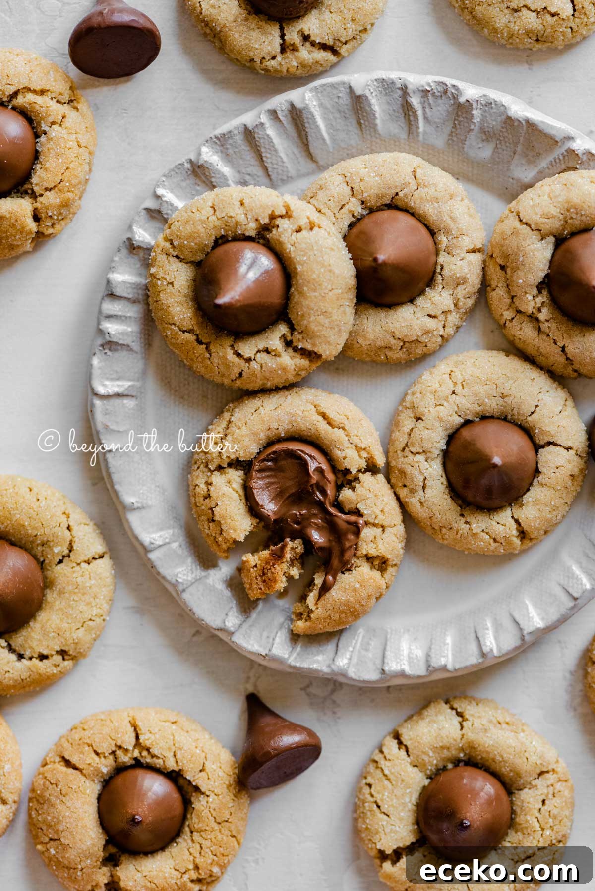 Classic Peanut Butter Blossoms Cookie Recipe 6 Small dessert plate full of classic peanut butter blossoms with one melted and split apart | All Images © Beyond the Butter™