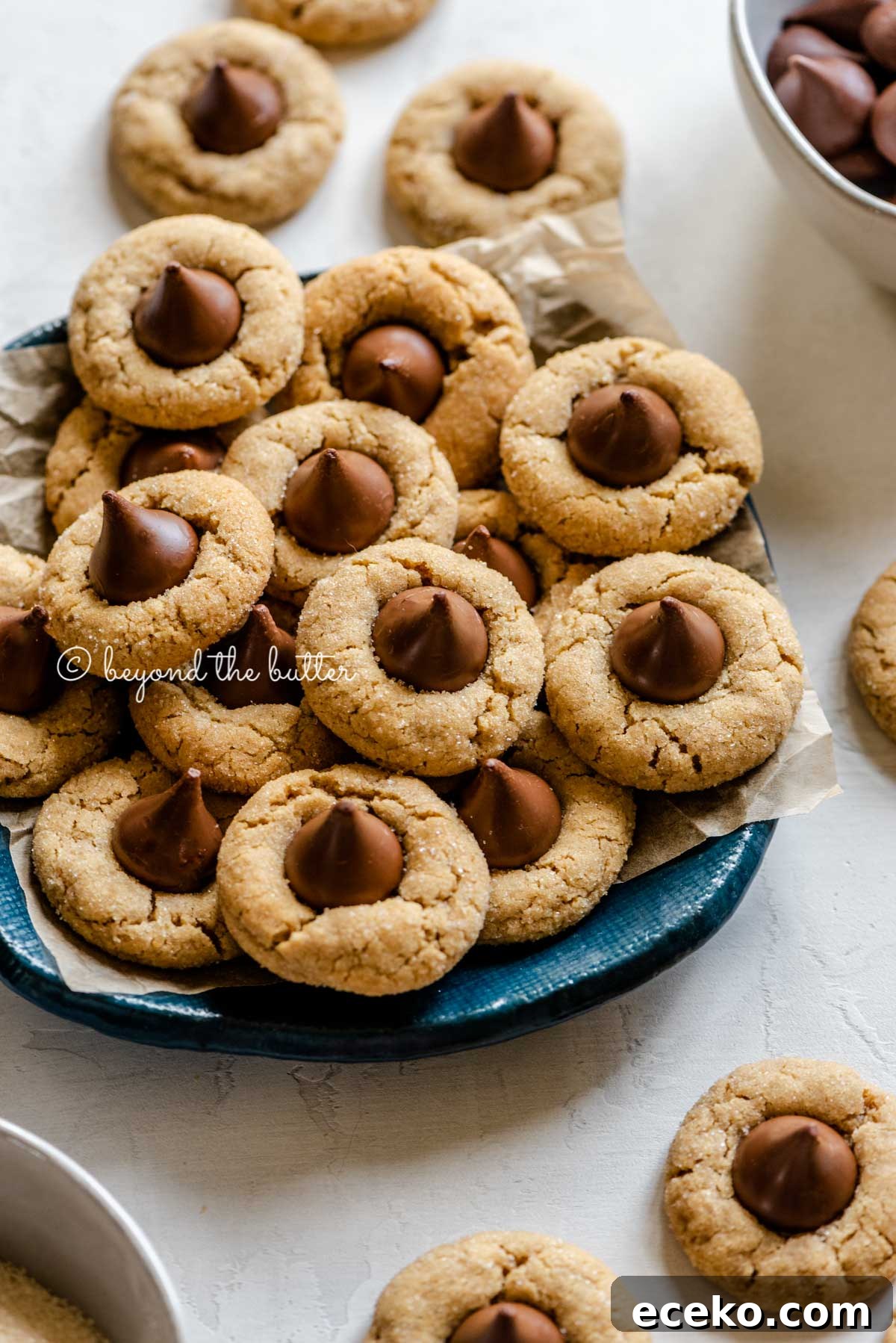 Classic Peanut Butter Blossoms Cookie Recipe 7 Angled image of classic peanut butter blossoms on a parchment lined blue dessert platter | All Images © Beyond the Butter™