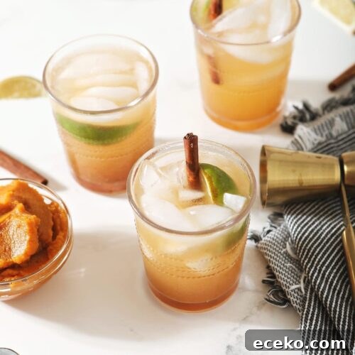 Three Pumpkin Mules, garnished with cinnamon sticks and lime wedges, surrounded by limes, pumpkin and a jigger on marble