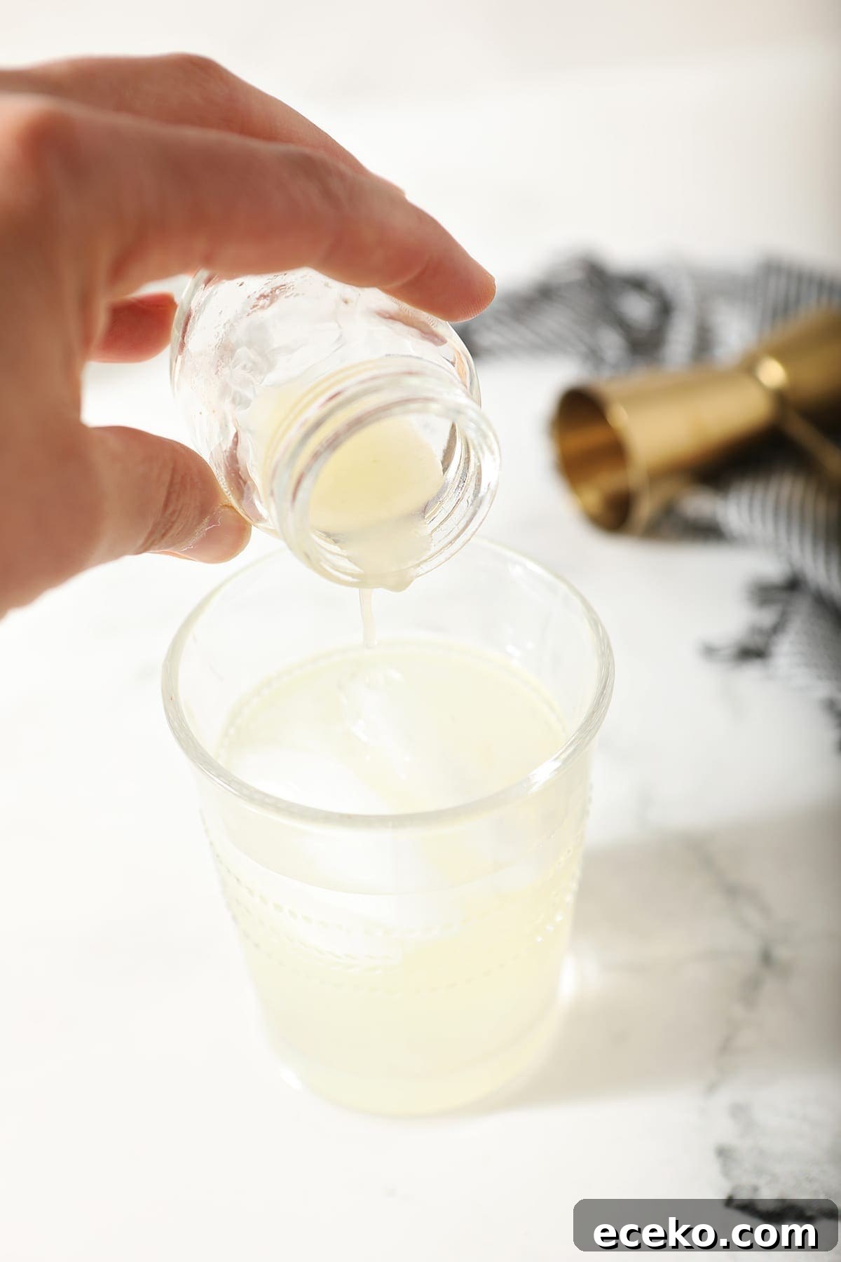 A hand pours lime juice into a ginger beer and vodka cocktail