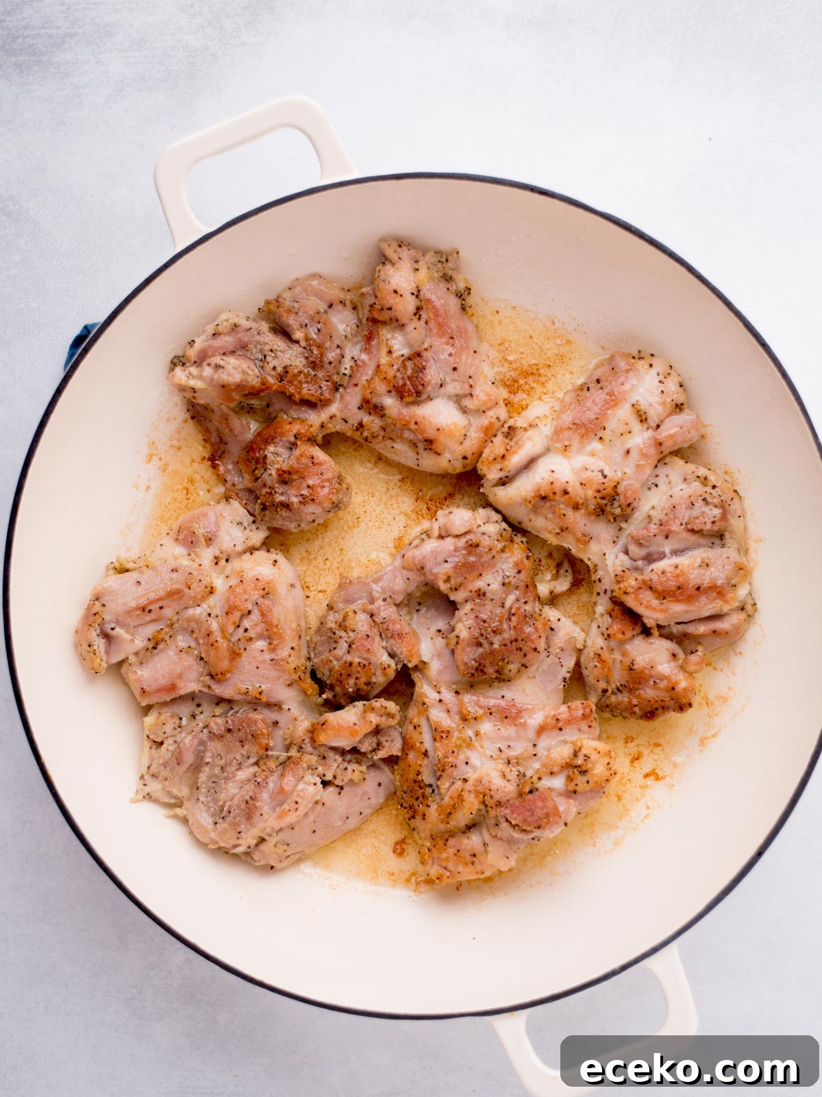 buffalo chicken thighs searing in a skillet