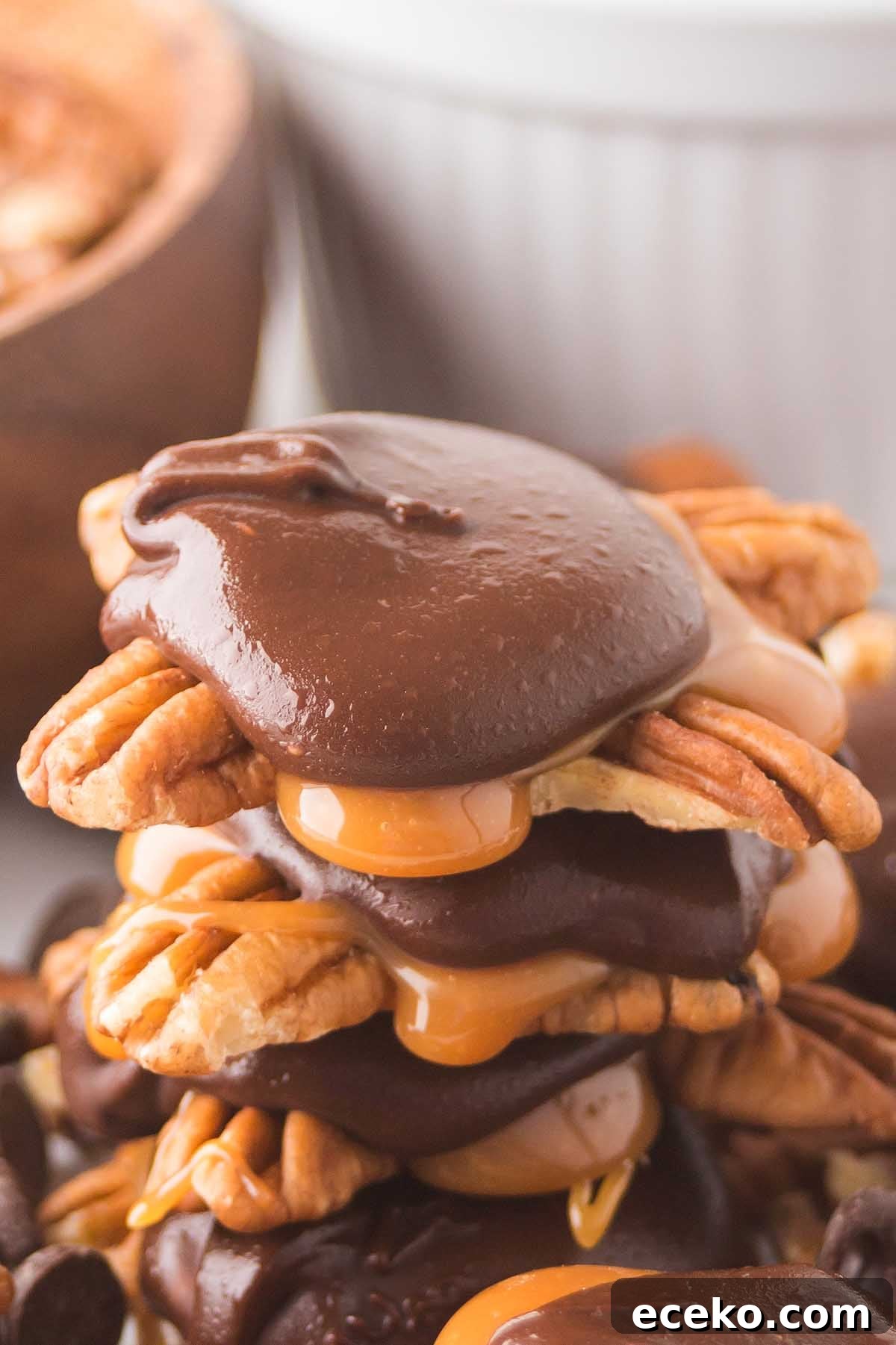 How to Make Classic Homemade Turtle Candies at Home 8 A stack of homemade turtles, chocolate and caramel-covered pecans, is piled on top of each other, with the glossy toppings dripping over the edges.