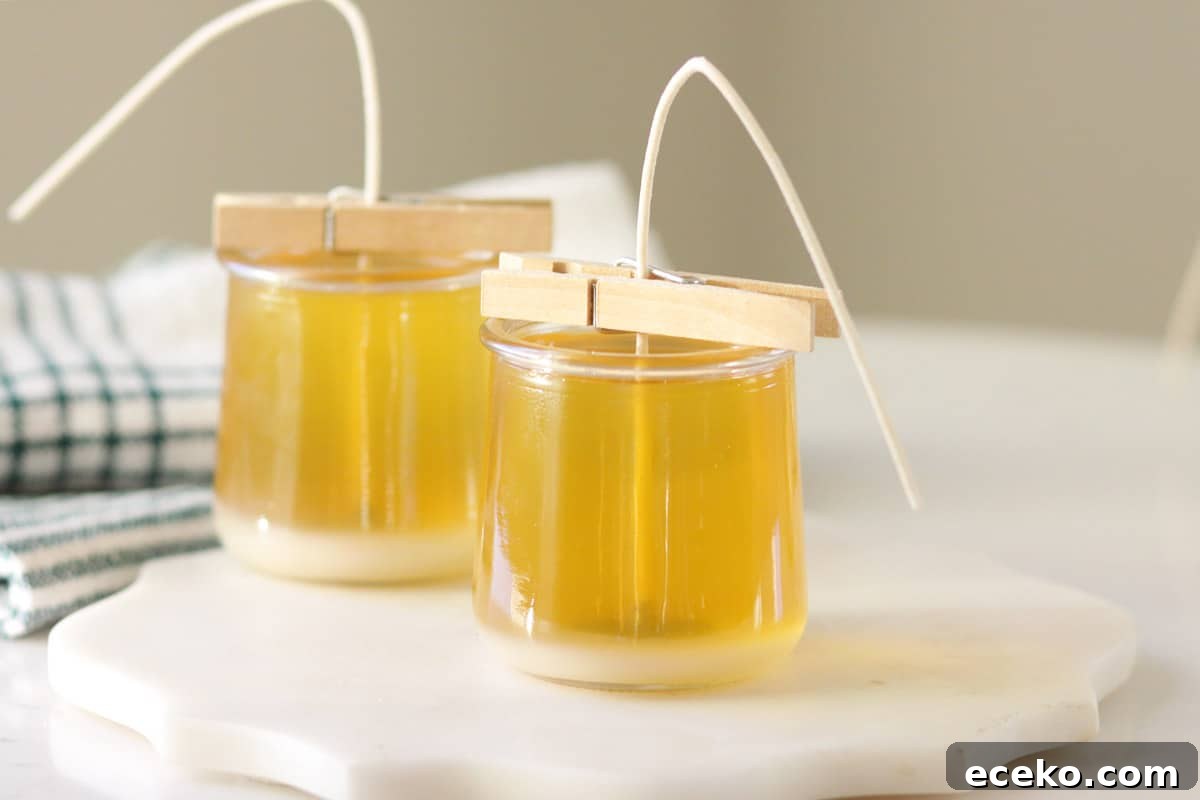 melted beeswax in two glass jars with wicks in the centers