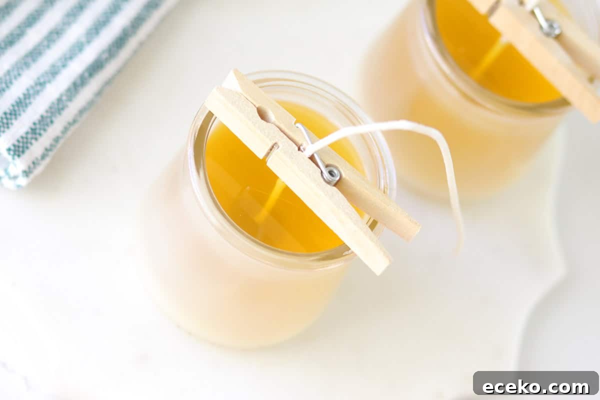 melted beeswax in two glass jars with wicks in the centers