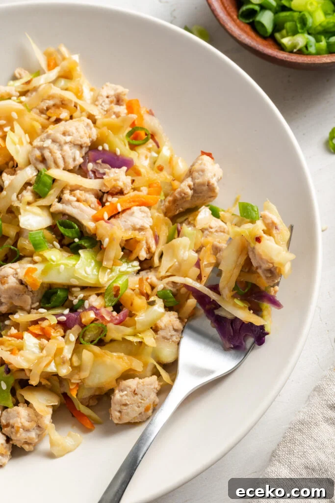 closeup shot of a plate of turkey egg roll in a bowl with a silver fork taking a bite.