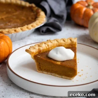 A photo of condensed milk pumpkin pie on a white plate topped with whipped cream