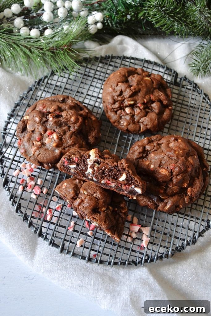 Chocolate Peppermint Cookies Inspired by Levain Bakery 5 an aerial shot of four levain chocolate peppermint cookies on a black wire rack surrounded by christmas pine