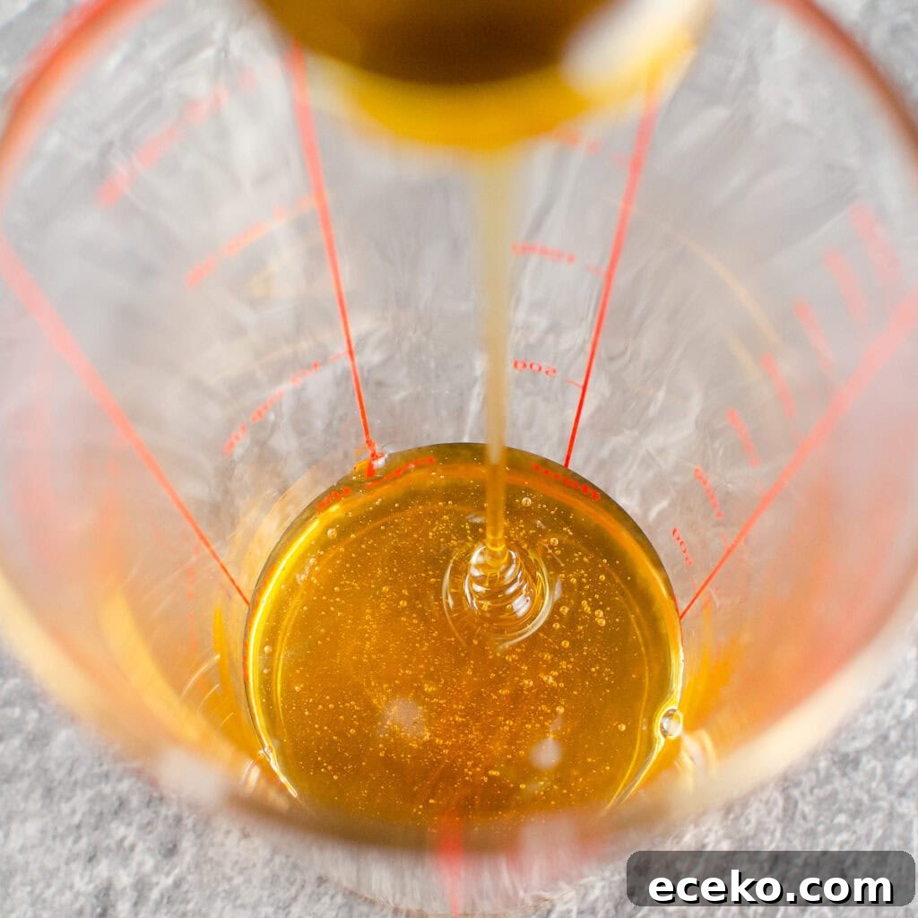 Honey-Glazed Roast Gammon Joint Recipe 21 Honey being poured into a clear glass measuring jug