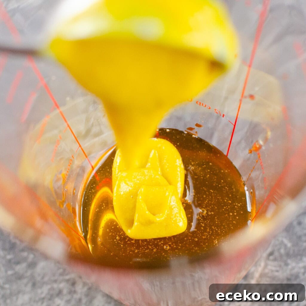 Honey-Glazed Roast Gammon Joint Recipe 22 English mustard being poured into a clear glass measuring jug