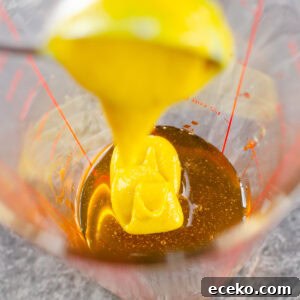 Honey-Glazed Roast Gammon Joint Recipe 6 English mustard being poured into a clear glass measuring jug