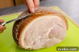 Honey-Glazed Roast Gammon Joint Recipe 7 Cutting the netting on a ham joint with a silver knife