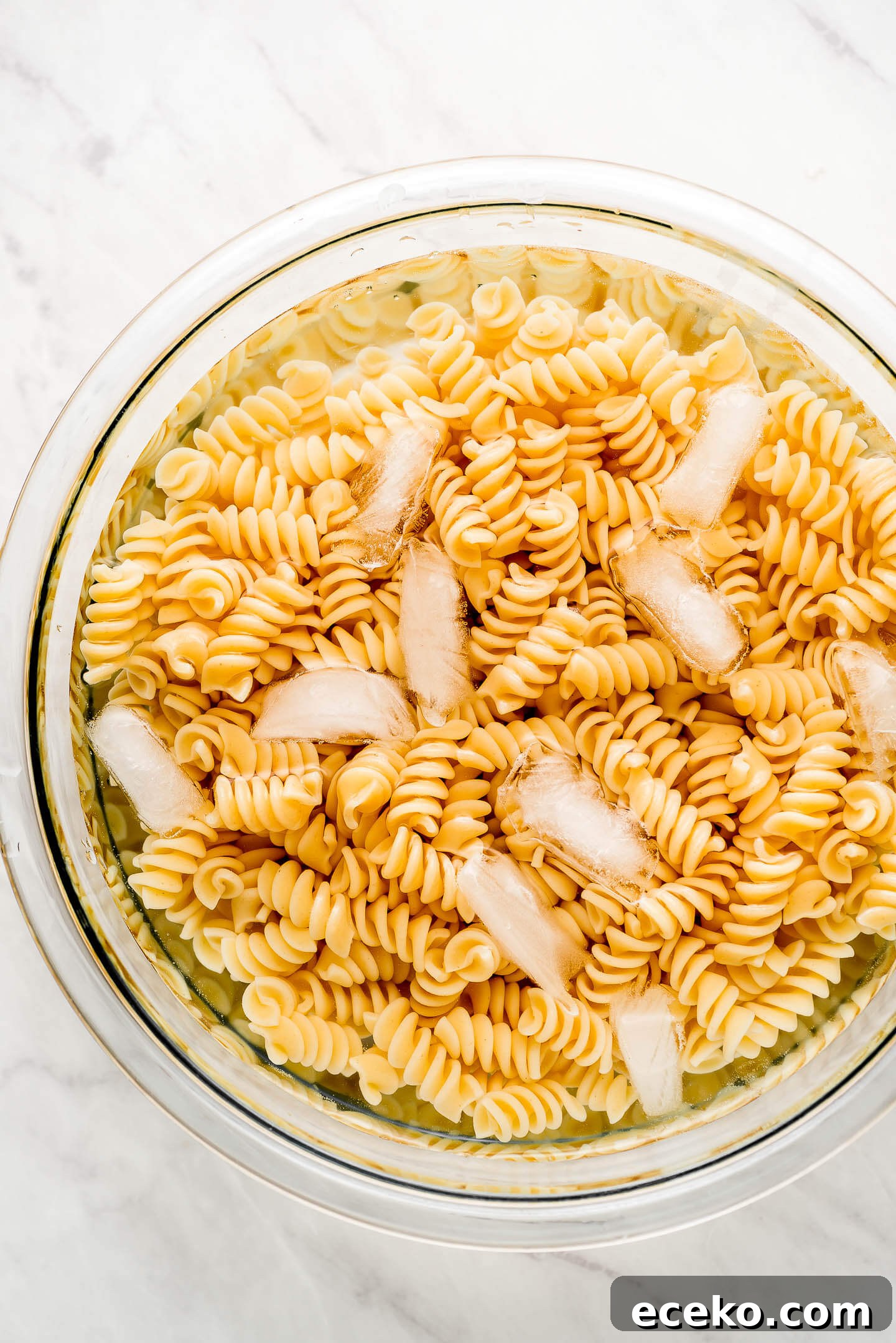 Creamy Chicken and Vegetable Pasta Salad Recipe 2 Cooked Rotini pasta in a bowl of ice water.