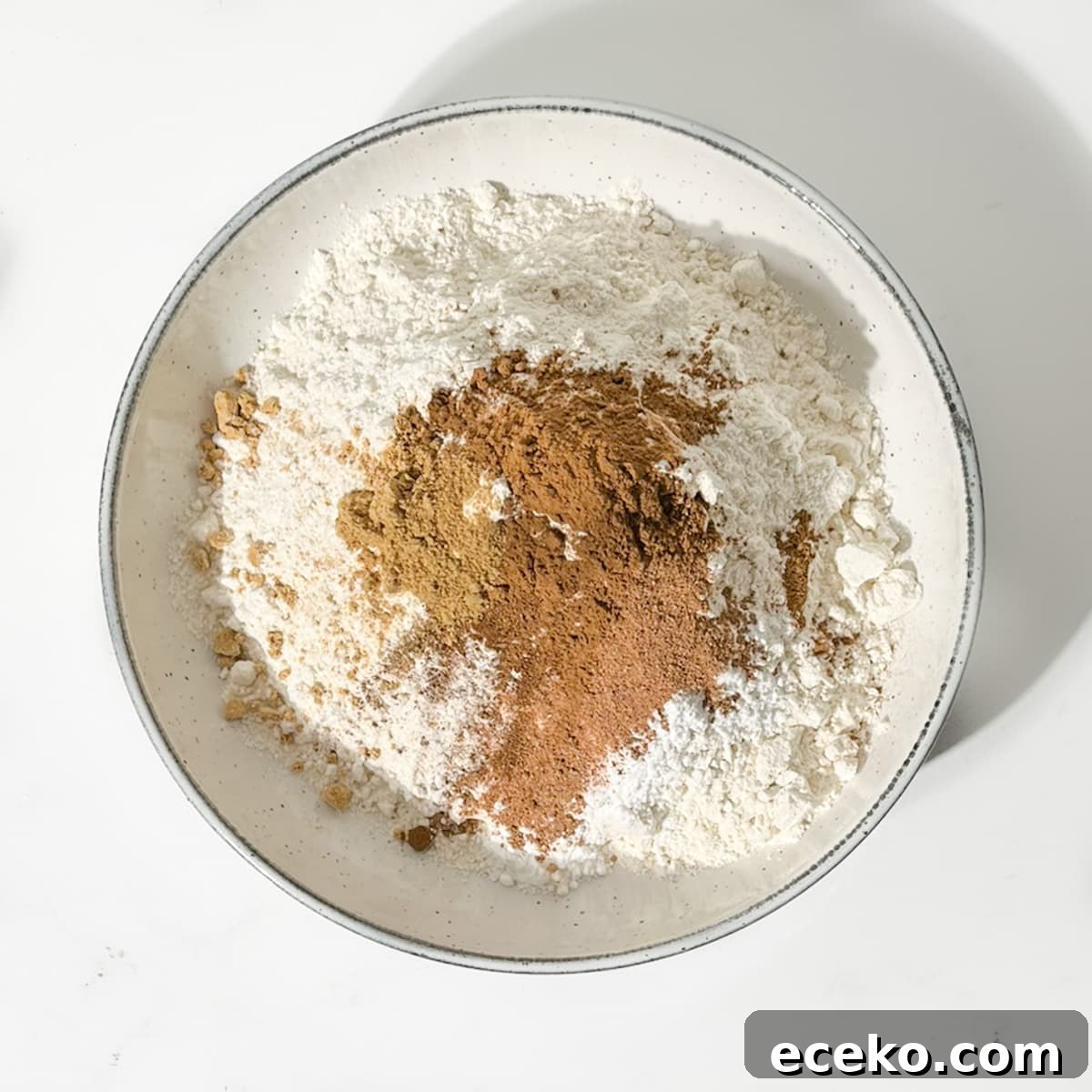 Adding spices to dry ingredients for spice biscuits.